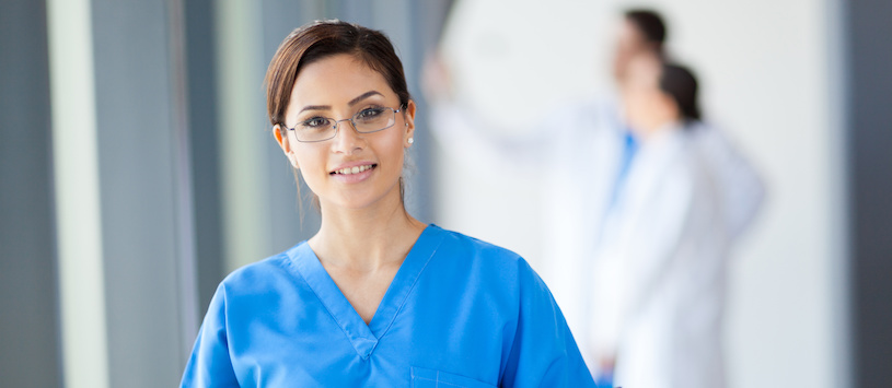 Woman in medical scrubs smiling in a medical setting.