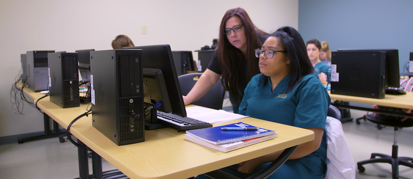 Student receiving help on the computer from her instructor.