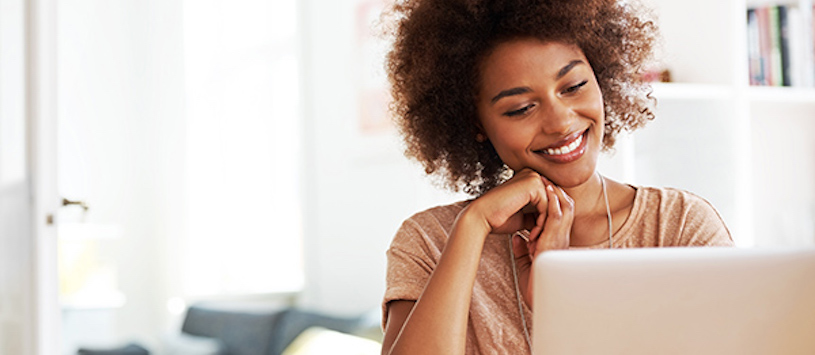 Woman using a laptop while smiling.